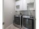 A well-lit laundry room featuring modern washer and dryer units with overhead storage at 9860 Smarty Jones Dr, Ruskin, FL 33573