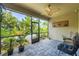 Relaxing screened-in patio with stone floors, ceiling fan, and view of the lush tropical landscaping at 9860 Smarty Jones Dr, Ruskin, FL 33573