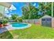 Backyard featuring a swimming pool, green lawn, shed and privacy fence at 11082 90Th Ter, Seminole, FL 33772