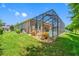 Backyard view showcasing the screened-in pool, green lawn, and the home's exterior at 1242 Windy Bay Shl, Tarpon Springs, FL 34689