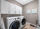 Well-equipped laundry room with modern machines, white cabinets, and wall art at 1242 Windy Bay Shl, Tarpon Springs, FL 34689