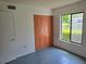 Bedroom with view of the lake and mature trees, bi-fold closet doors, and tile floors at 1281 Pine Ridge E Cir # B1, Tarpon Springs, FL 34688