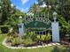 Welcoming Pine Ridge at Lake Tarpon community sign amidst beautiful landscaping and bright sunshine at 1281 Pine Ridge E Cir # B1, Tarpon Springs, FL 34688