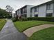 Well-maintained condo building with lush landscaping and walking path leading to the entrance at 1281 Pine Ridge E Cir # B1, Tarpon Springs, FL 34688