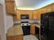 Kitchen featuring granite countertops, wood cabinets, black appliances, and tile floors at 1281 Pine Ridge E Cir # B1, Tarpon Springs, FL 34688