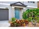 Charming front entrance featuring a blue door, manicured landscaping, and a two car garage at 12835 Wildflower Meadow Dr, Riverview, FL 33579