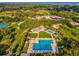 Expansive aerial shot of a community park featuring swimming pools, tennis courts, and playgrounds surrounded by trees at 1340 Bayshore Blvd # 502, Dunedin, FL 34698