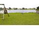 Spacious backyard with a wooden swing set, a wooden fence, and a serene view of the tranquil lake at 1423 Birchstone Ave, Brandon, FL 33511