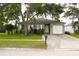 Exterior elevation of a one story home shows a well manicured lawn, mature trees and an attached one car garage at 1423 Birchstone Ave, Brandon, FL 33511