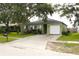 Exterior elevation of a one story home shows a well manicured lawn, mature trees and an attached one car garage at 1423 Birchstone Ave, Brandon, FL 33511