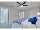 Bright bedroom with a ceiling fan, crisp white bedding and a blue accent blanket, and an en suite bathroom at 1506 Winding W Way, Clearwater, FL 33764
