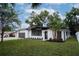 This home features a white exterior, dark trim, manicured landscaping, and an attached garage, offering both curb appeal at 1506 Winding W Way, Clearwater, FL 33764