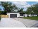 Modern single-story home with a gray garage door, fresh white exterior paint, and a concrete driveway with gravel at 1506 Winding W Way, Clearwater, FL 33764