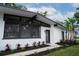 The exterior features a mix of modern design with large windows and brick, enhanced by lush landscaping and mature palms at 1506 Winding W Way, Clearwater, FL 33764