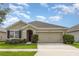 Charming single-story home featuring a two-car garage, well-manicured lawn, and classic architectural details at 15406 Gopher Trop Pl, Sun City Center, FL 33573