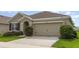 Close-up of the two-car garage with a driveway and well-kept bushes at 15406 Gopher Trop Pl, Sun City Center, FL 33573