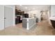 Well-lit kitchen featuring dark cabinets, black appliances, and a central island with tile flooring at 15406 Gopher Trop Pl, Sun City Center, FL 33573