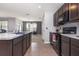 Open kitchen with dark cabinets, tile floor, and an island sink overlooking the living room at 15406 Gopher Trop Pl, Sun City Center, FL 33573