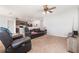 Open-concept living room with carpet, ceiling fan, and leather furniture, seamlessly connecting to the kitchen at 15406 Gopher Trop Pl, Sun City Center, FL 33573