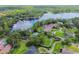 Aerial view of luxury homes with manicured lawns and swimming pools on a lake with mature trees at 16205 Sentry Woods Ct, Odessa, FL 33556