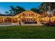 Charming backyard with lush green lawn, stone patio, outdoor seating, and ambient lighting for relaxing and entertaining at 16205 Sentry Woods Ct, Odessa, FL 33556