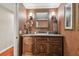 Powder room with dark wood vanity, a decorative mirror, and neutral wallpaper at 16205 Sentry Woods Ct, Odessa, FL 33556