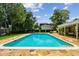 The pool area is surrounded by lush greenery and a stone patio with outdoor seating at 16205 Sentry Woods Ct, Odessa, FL 33556
