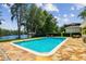 Relaxing backyard pool with stone patio and lake views, surrounded by mature trees at 16205 Sentry Woods Ct, Odessa, FL 33556
