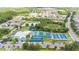Wide aerial view of a community featuring a recreational area with pools, courts, and a playground amidst lush greenery at 1914 Sassafras Dr, Wesley Chapel, FL 33543