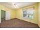 A sunny bedroom with yellow walls, carpet floors and a ceiling fan creates a bright and inviting atmosphere at 1914 Sassafras Dr, Wesley Chapel, FL 33543