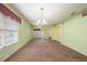 Bright living room with a hanging light fixture, neutral carpet, and views of the home's exterior at 1914 Sassafras Dr, Wesley Chapel, FL 33543