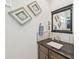 Bathroom vanity with a dark countertop, framed seashell art, and a decorative mirror at 200 Eppinger Dr, Port Charlotte, FL 33953