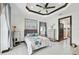 Bedroom with a tray ceiling, fan, tiled floors, and a doorway to an ensuite bathroom at 200 Eppinger Dr, Port Charlotte, FL 33953