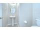 Bathroom with pedestal sink, decorative mirror, toilet, and tile floor at 208 English Heritage Pl, Dover, FL 33527