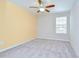 A bright bedroom with neutral carpet, ceiling fan, and a window with blinds at 208 English Heritage Pl, Dover, FL 33527