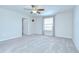 Bright carpeted bedroom features a ceiling fan, window, and a doorway leading to an adjacent room at 208 English Heritage Pl, Dover, FL 33527