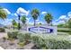 Dover Ridge community entrance featuring lush landscaping, a decorative sign, and palm trees against a blue sky at 208 English Heritage Pl, Dover, FL 33527