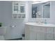 Bathroom featuring a white vanity with cabinet storage, a decorative mirror, and a shower behind an open door at 2333 Feather Sound Dr # B609, Clearwater, FL 33762