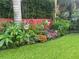 Picturesque backyard garden with vibrant flowers, a red fence, a lush lawn, and tropical plants at 243 Snell Isle Ne Blvd, St Petersburg, FL 33704