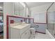 Cozy bathroom with a sink, toilet with grab bars, and shower with classic red and blue accent tiling at 243 Snell Isle Ne Blvd, St Petersburg, FL 33704
