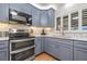 Updated kitchen features stainless steel appliances, including oven and microwave, blue cabinets, and a decorative backsplash at 243 Snell Isle Ne Blvd, St Petersburg, FL 33704