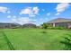 Expansive green backyard with a view of neighboring homes and a serene lake at 271 Monet Trl, Bradenton, FL 34212