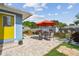 Backyard brick patio with an umbrella-covered table and chairs, with the exterior house paint in blue and yellow at 4211 28Th N Ave, St Petersburg, FL 33713