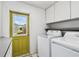 Bright laundry room with a modern washer and dryer, white cabinets, and a yellow door to the exterior at 4211 28Th N Ave, St Petersburg, FL 33713