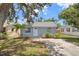 Charming single-story home with gray exterior paint, fresh landscaping, and a concrete driveway, nestled beneath a large tree at 4870 47Th N Ave, St Petersburg, FL 33714