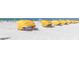 Sandy beach featuring rows of yellow beach umbrellas, ideal for a relaxing day by the ocean at 505 67Th Ave # 11, St Pete Beach, FL 33706