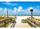Scenic beach view from wooden stairs, showcasing the white sand, beach umbrellas, and ocean at 505 67Th Ave # 11, St Pete Beach, FL 33706