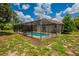 Exterior shot of the backyard with an in-ground pool featuring a screened-in lanai at 6123 India Dr, Spring Hill, FL 34608