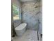 Luxurious bathroom featuring a freestanding tub, marble tiling, a window, and a golden shower head at 6332 Emerson S Ave, St Petersburg, FL 33707
