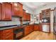 Updated cherry wood kitchen with stainless steel appliances, black countertops, tile backsplash, and hard wood floors at 6543 Louise Ct, Hudson, FL 34667